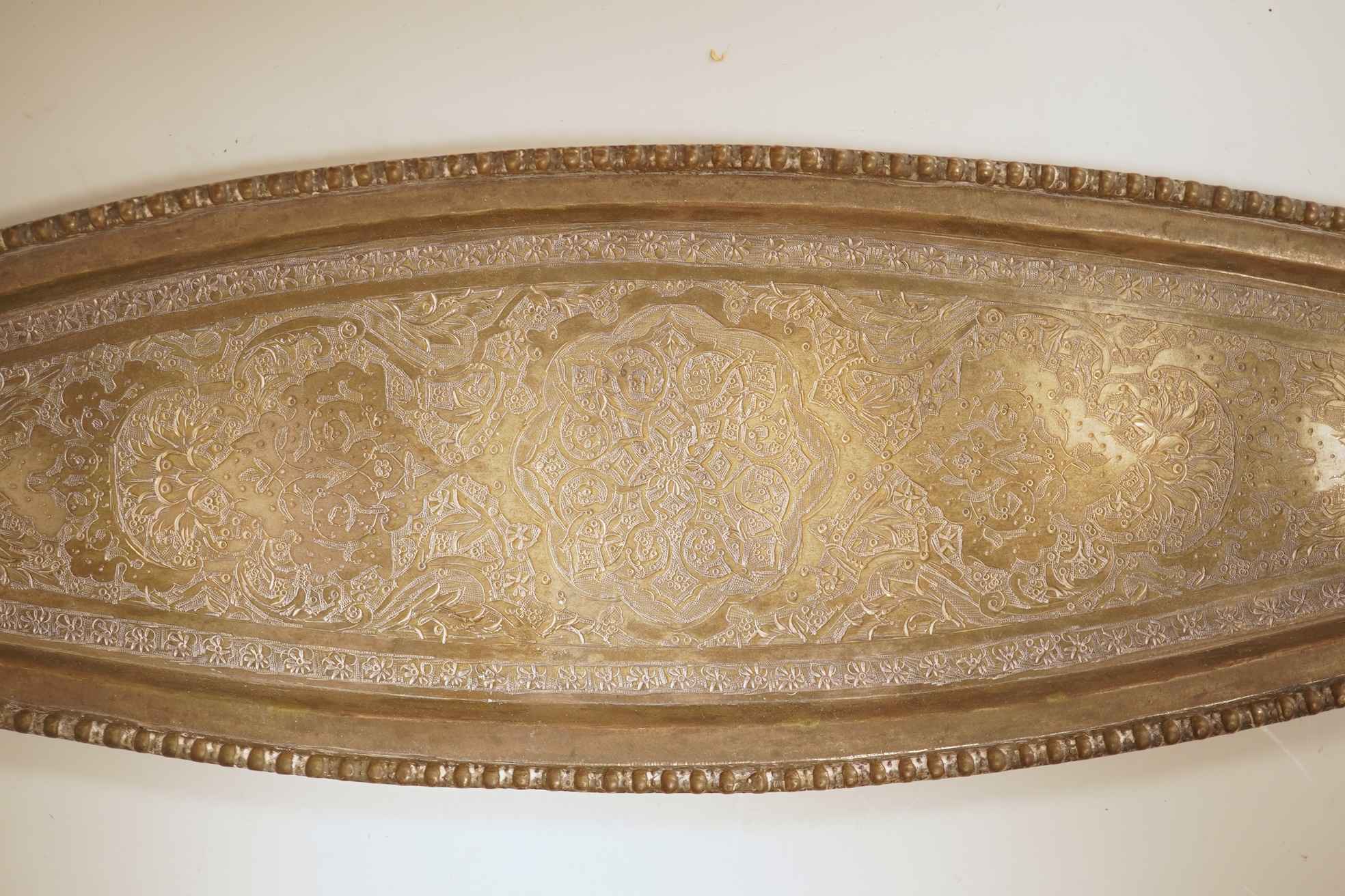 A set of six 20th century Middle Eastern white metal tots, 42mm and matching tray, 25.2cm, all engraved with geometric foliate decoration.